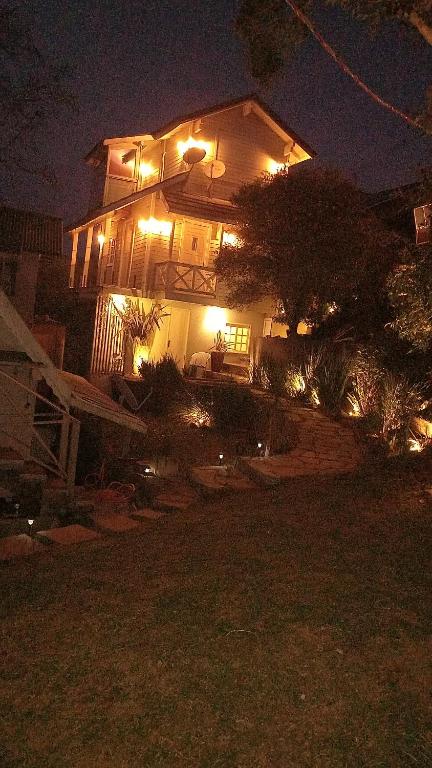 een huis verlicht 's nachts met lichten aan bij Casa chalé inteira gramado in Gramado