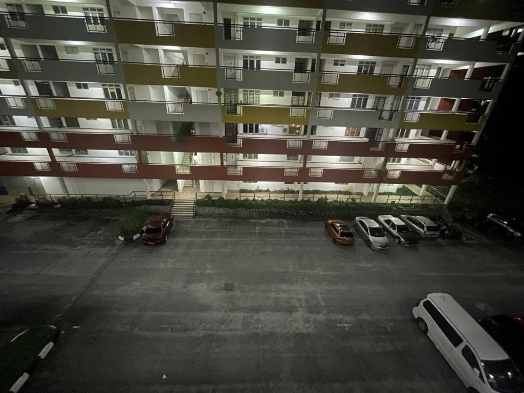 un gran edificio de apartamentos con coches aparcados en un aparcamiento en Elvina Guesthouse @ Laguna Condo Resort PD en Kampong Tanah Merah
