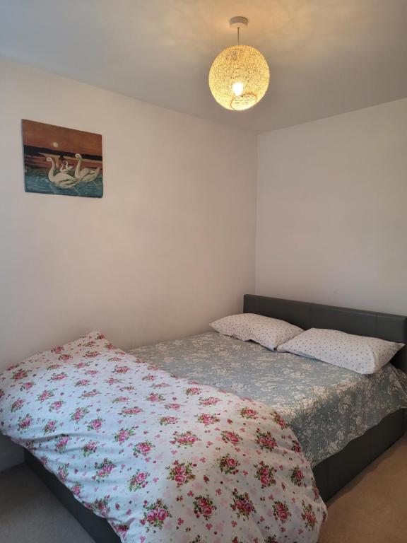 1 Schlafzimmer mit einem Bett mit Blumendecke in der Unterkunft Room near Heathrow Airport in New Bedfont