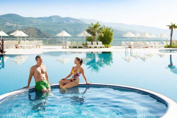 a man and a woman sitting in a swimming pool at CLC Wyndham Kuşadası Golf resort in Soke