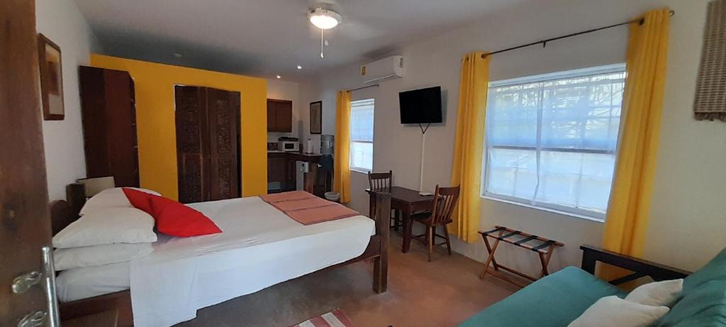 a bedroom with a bed and a living room at Amanda's Place Yellow Studio - Pool and Tropical garden in Caye Caulker