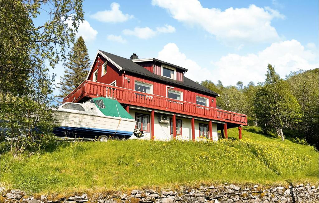 a red house with a boat on a hill at Beautiful Home In Bogen I Ofoten With Wifi in Bogen