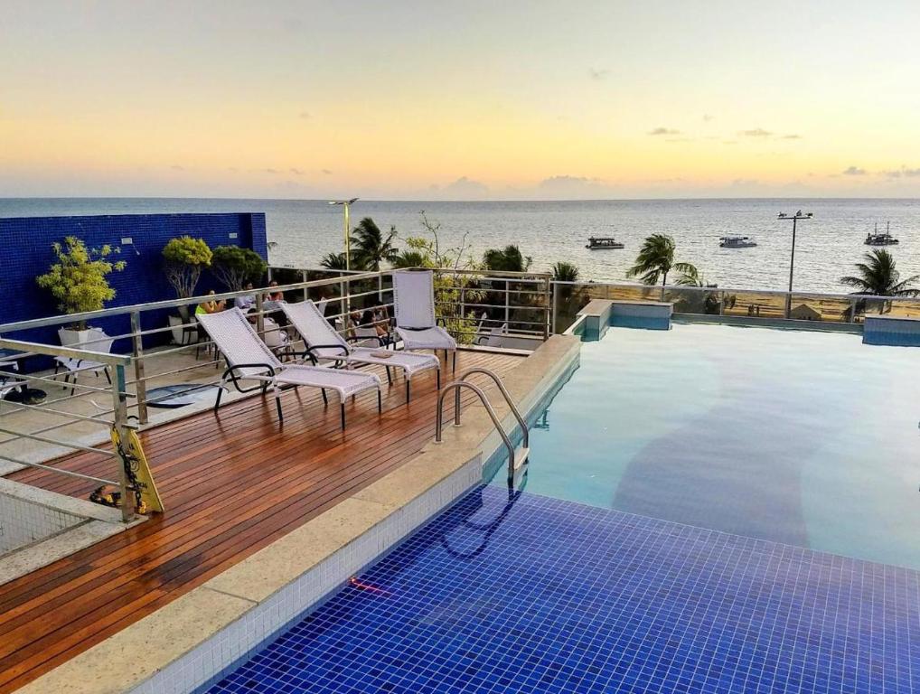 a swimming pool with chairs on a balcony overlooking the ocean at Apartamento com vista para a orla de Tambaú, apt 206 in João Pessoa