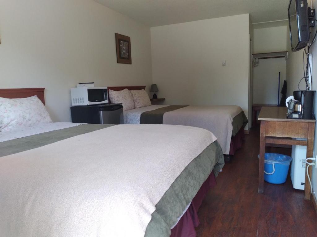 a hotel room with two beds and a microwave at Dolphin Motel in Tofino