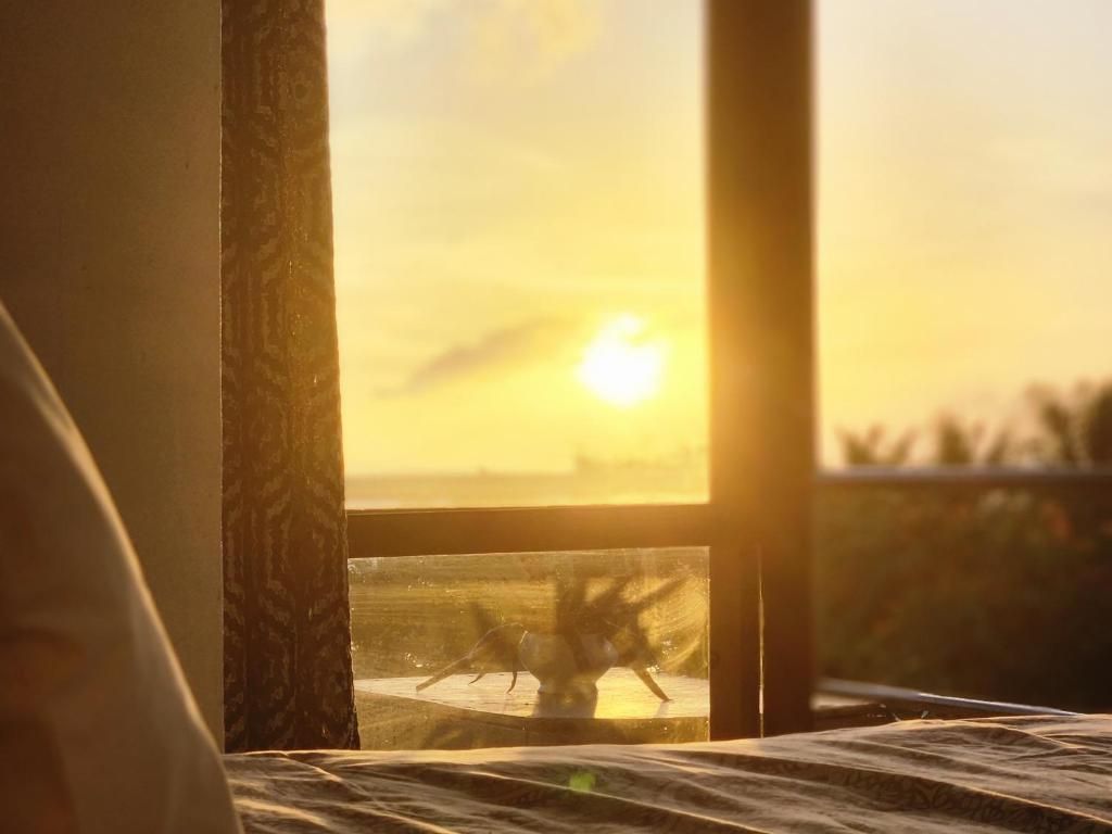une fenêtre avec vue sur le coucher du soleil dans l'établissement Eua Accommodation, à ‘Ohonua