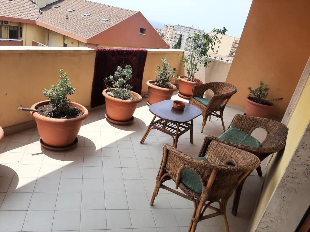 een balkon met stoelen, tafels en potplanten bij B&B Lumière in Reggio di Calabria
