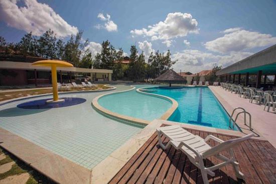 uma grande piscina com cadeiras e um guarda-sol em Flat Fazenda Monte Castelo Gravatá em Gravatá
