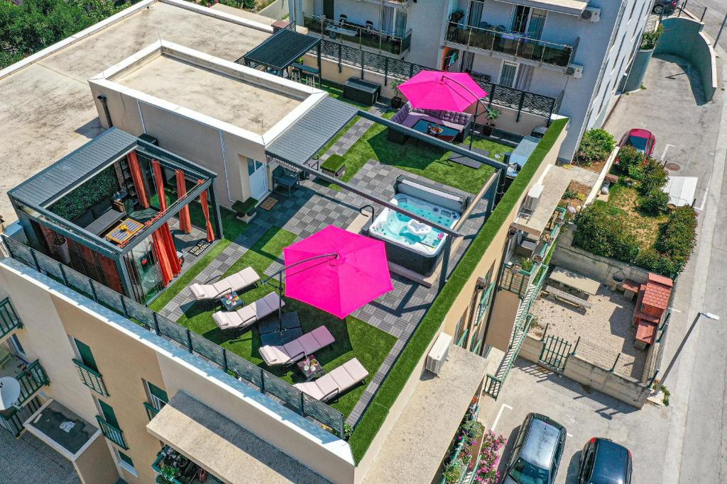 una vista aérea de una casa con piscina y sombrillas rosas en Apartments with a parking space Kastel Gomilica, Kastela - 21138, en Kaštela