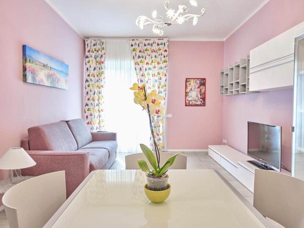アローナにあるCasa Ierardi - Appartamento Aronaのピンクの壁のリビングルーム(テーブル付)