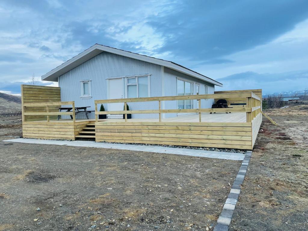 a house with a wooden fence in front of it at Stylish cottage with hot tub in Stóri-Ás