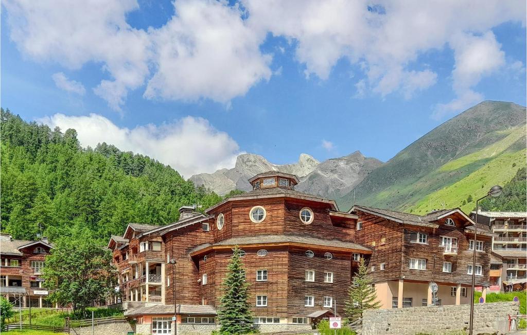 a large brick building with mountains in the background at 1 Bedroom Lovely Apartment In Allos in La Foux