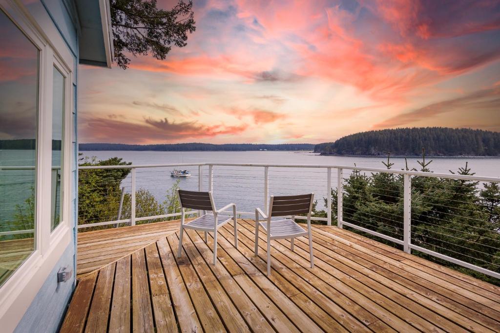 two chairs on a deck with a view of the water at The Cliffside Poustinia in Kodiak