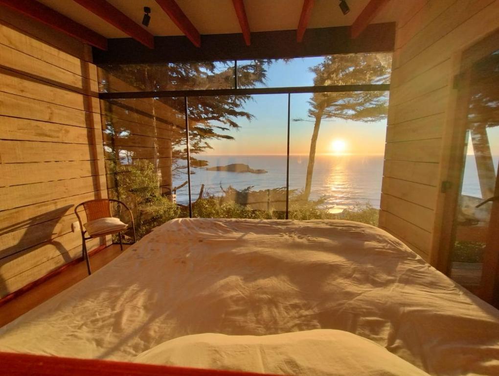 a bed in a room with a view of the ocean at Cabaña Rustica en lagunillas con vista al mar in Navidad