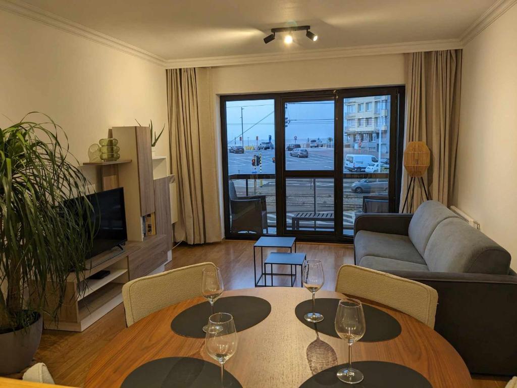 ein Wohnzimmer mit zwei Tischen und Weingläsern darauf in der Unterkunft Vista Linda, leuk appartement vlak bij zeedijk en strand in Ostende