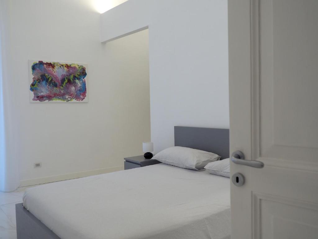 una camera bianca con un letto e un dipinto sul muro di SANTACROCE8 a Torre del Greco