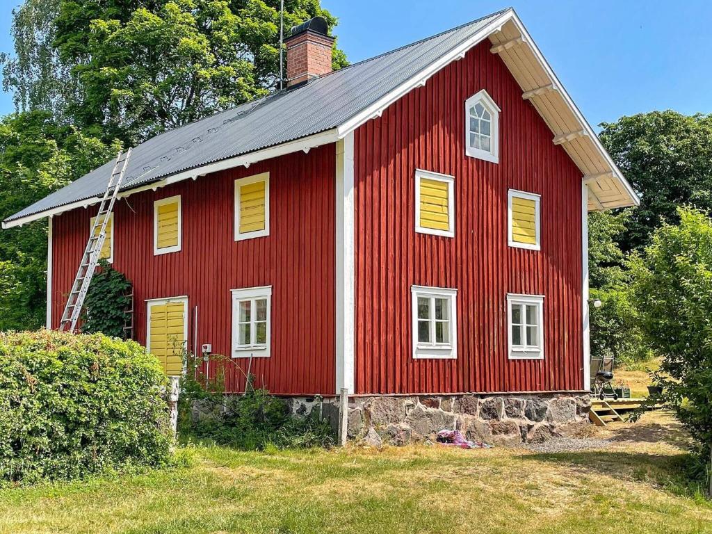 a red barn with yellow shutters on it at Holiday home VALDEMARSVIK VIII in Valdemarsvik