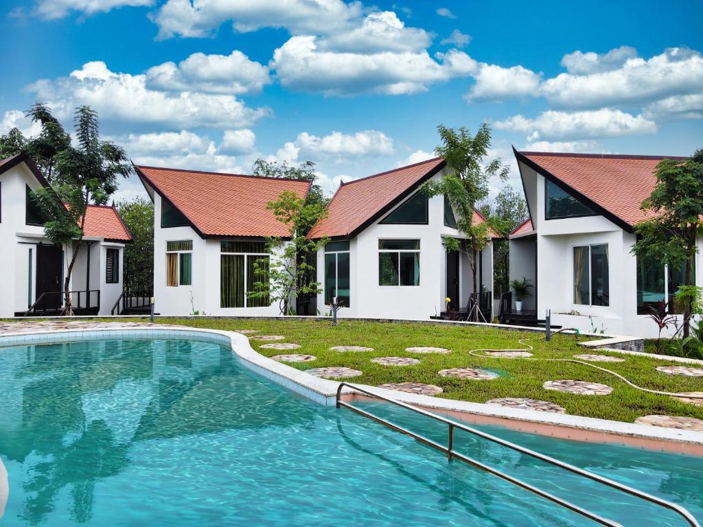 a villa with a swimming pool in front of a house at LA PETITE MANGROVE Resort in Phumĭ Srângam