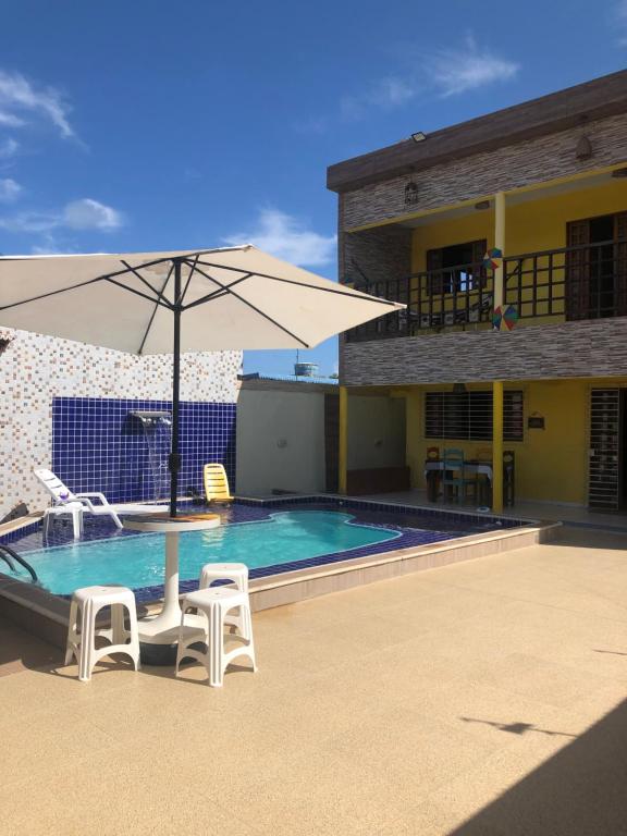 - une piscine avec 2 chaises et un parasol dans l'établissement Paraíso dos Oliveira, à São José da Coroa Grande