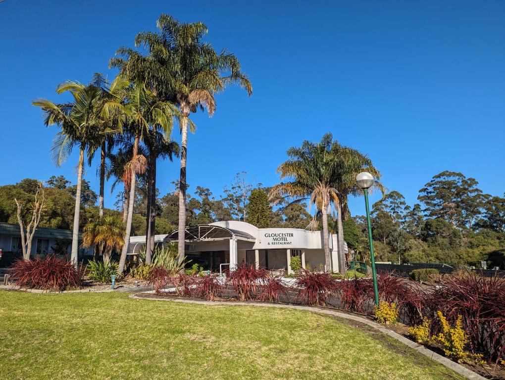 un parc avec des palmiers en face d'un bâtiment dans l'établissement Gloucester Motel Pemberton Manjimup, à Pemberton