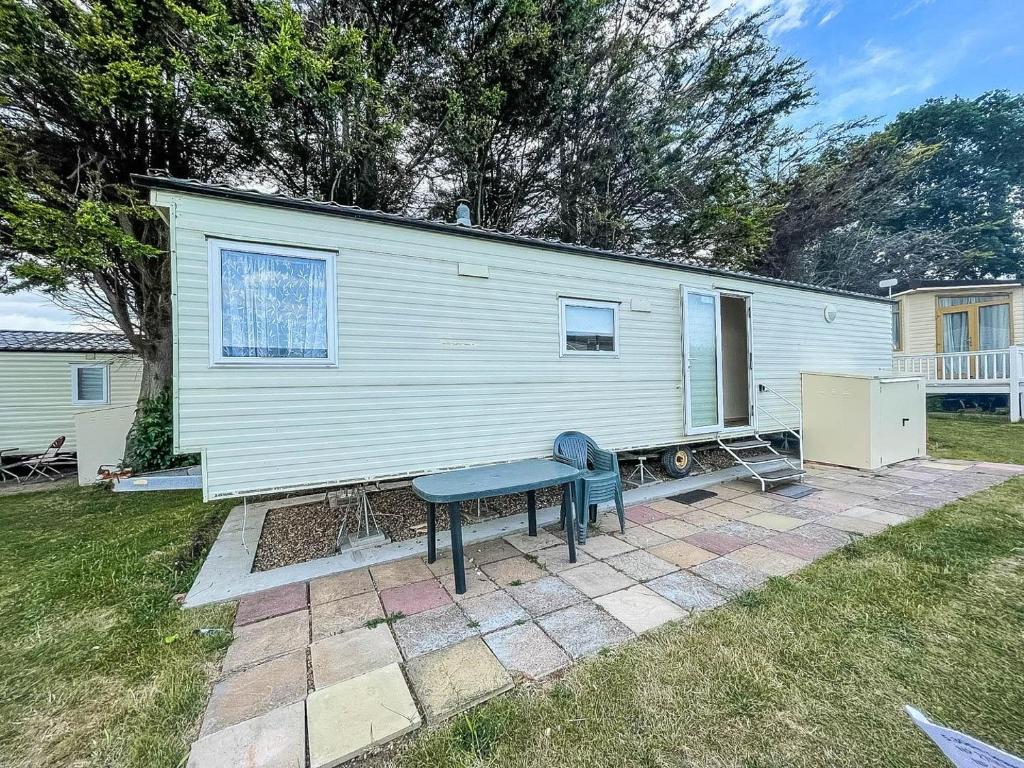 una casa pequeña con una mesa de picnic en un patio en Lovely Caravan At Valley Farm Holiday Park, Sleeps 8 Ref 46127v, en Great Clacton