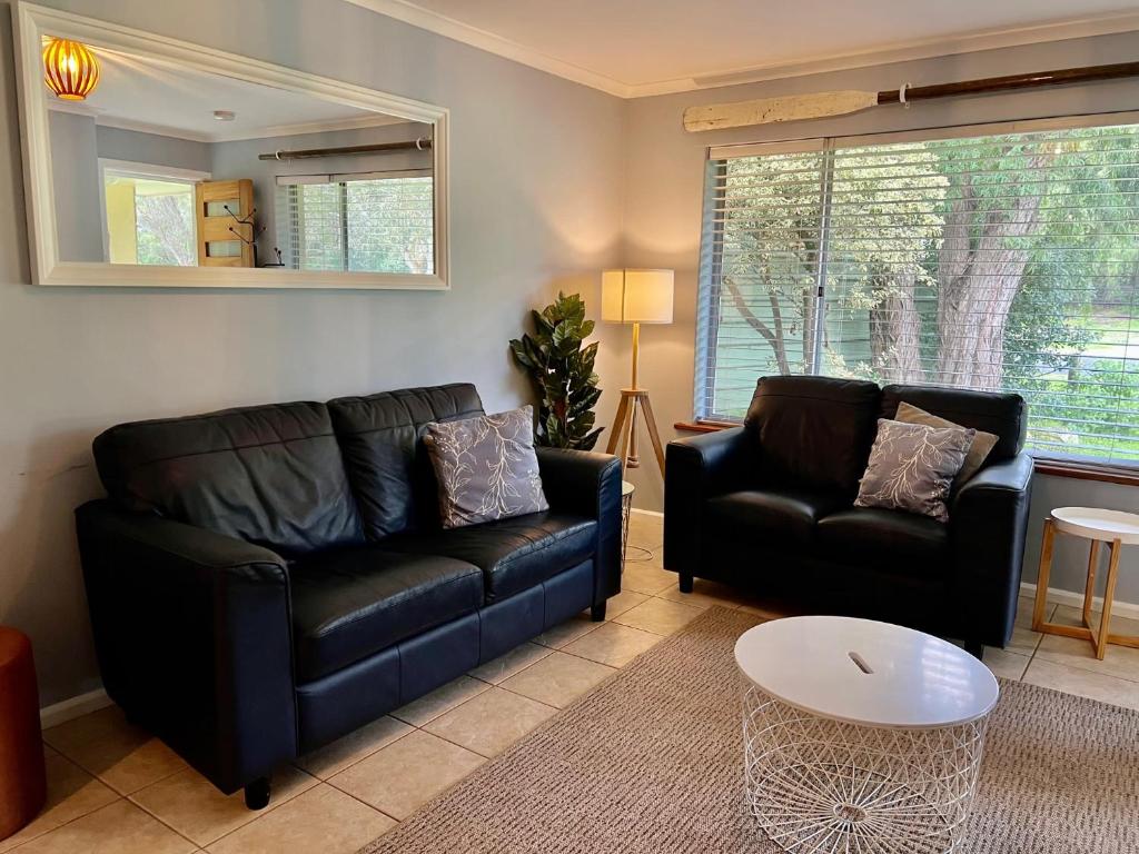 a living room with two black leather couches and a table at Wrentree - Pet Friendly Inside 26B Laurel Tce in Robe