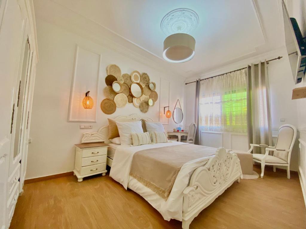 una camera con un letto bianco, una sedia e una finestra di Appartement LOUIS XIV avec HAMMAM SAUNA JACCUZI PRIVATISÉ TOTALEMENT GRATUIT SANS SUPPLÉMENT ! ad Al-Ḥoseyma