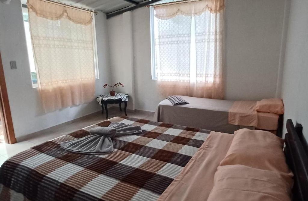 a bedroom with two beds and a table and windows at Mindomundo Home in Mindo