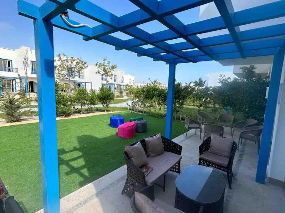 a patio with chairs and tables under a blue pergola at 4Bedroom villa in pharos in Mountain view 98 B in Zāwiyat al ‘Awwāmah