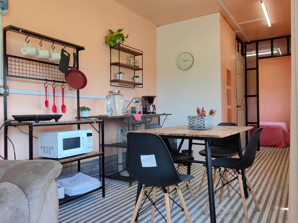 a living room with a table and chairs and a microwave at Casa contenedor Finca la laguna in Córdoba