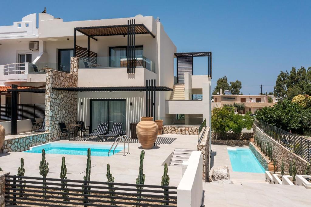 a villa with a swimming pool and a house at Nόka Suite Apartments in Faliraki