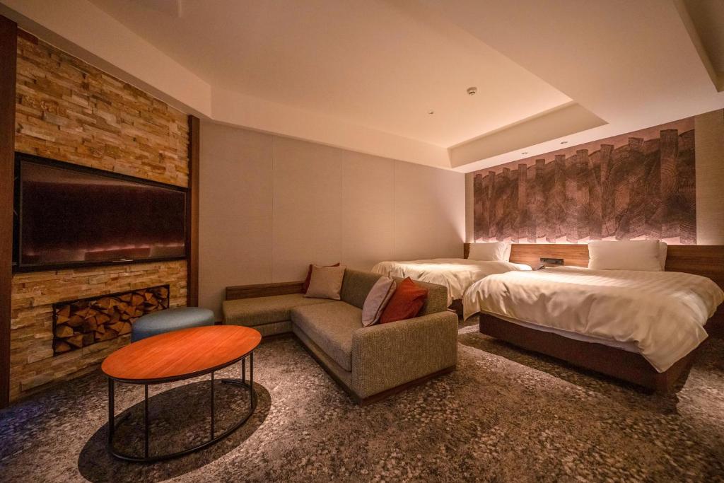 a hotel room with two beds and a couch at Kusatsu Now Resort Hotel in Kusatsu