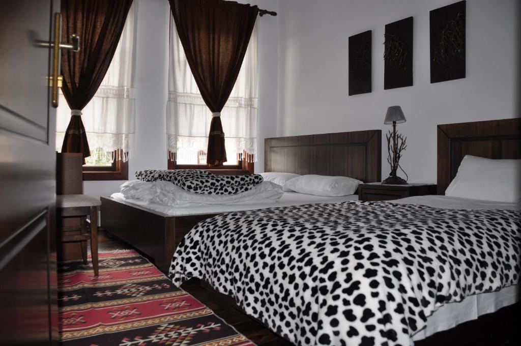 a bedroom with two beds with black and white sheets at Hotel Belgrad Mangalem in Berat