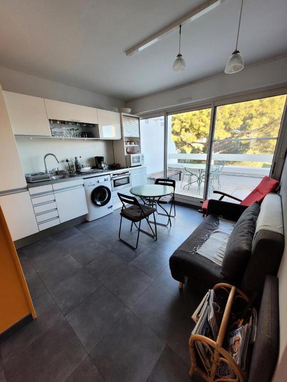 Il dispose d'une cuisine et d'un salon avec un canapé et une table. dans l'établissement Le Birdy - maeva Home - Appartement 2 pièces 4 personnes - Prestige 614, à La Grande Motte