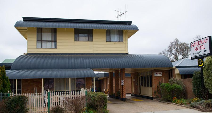 a yellow building with a sign in front of it at Parkway Motel in Queanbeyan
