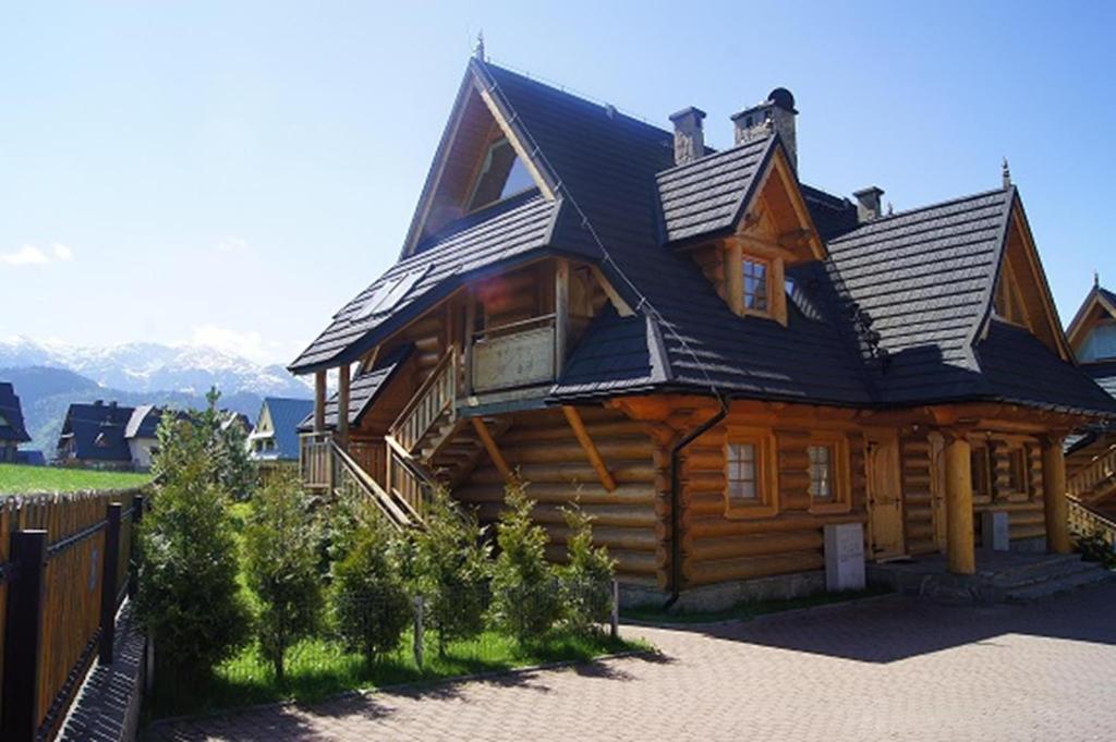 a large wooden cabin with a black roof at Apartament Mountain View in Kościelisko