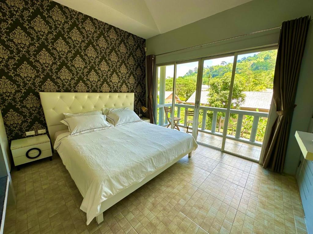 1 dormitorio con cama blanca y balcón en Peaceful Retreat Villa by Nai Thon beach en Phuket