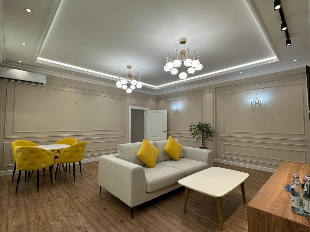 ein Wohnzimmer mit einem Sofa, einem Tisch und gelben Stühlen in der Unterkunft Home Apartment Luxe in Schymkent