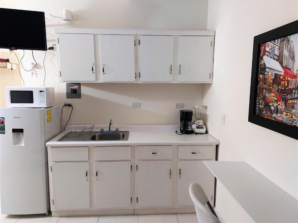 a kitchen with white cabinets and a sink and a refrigerator at Loft 15 comodo y confortable , cerca del centro de gobierno , galerias mall, consulado , CAS , Pepsi in Hermosillo