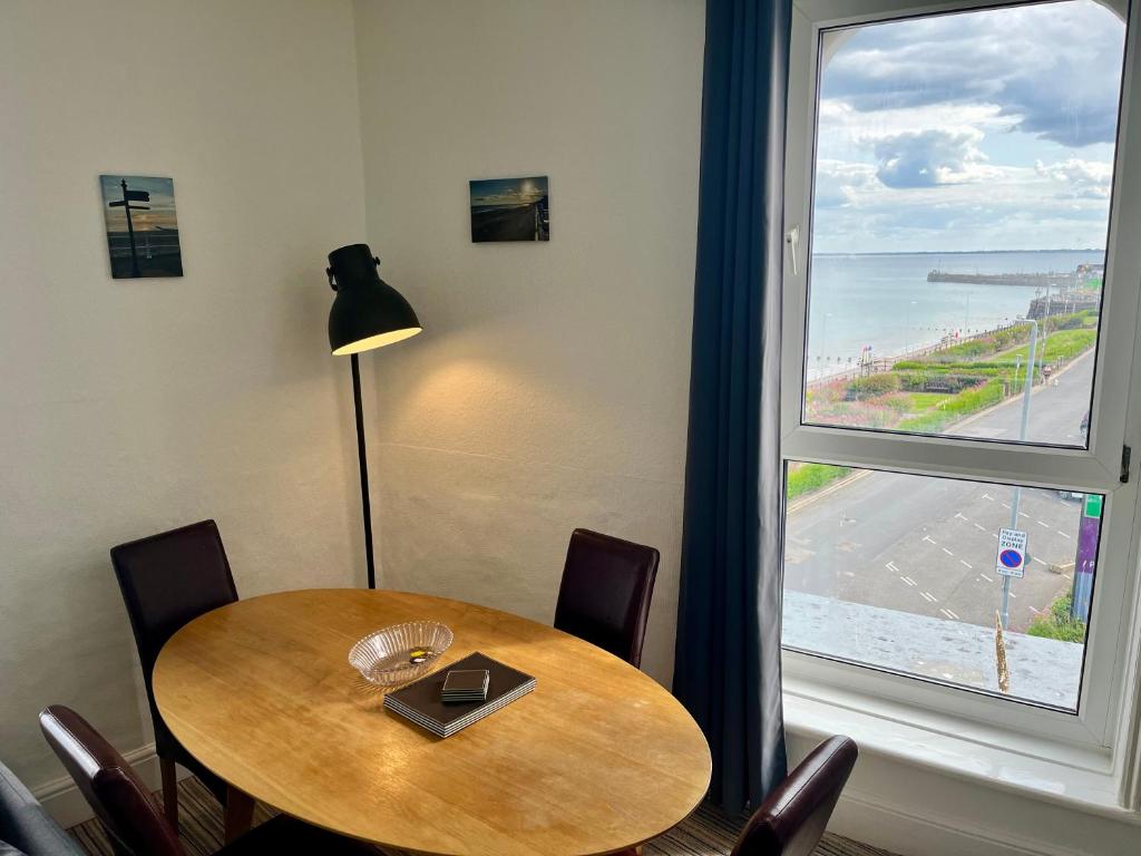 a table with chairs and a window with a view of the ocean at 7 Beach View Beaconsfield House in Bridlington
