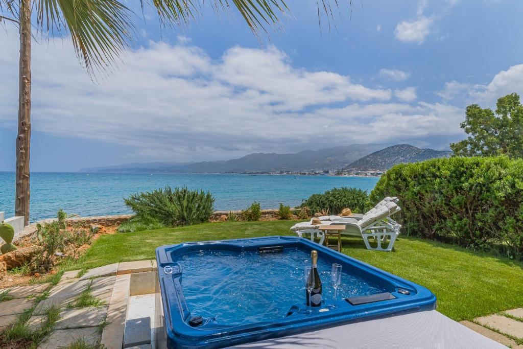 - une piscine bleue avec une bouteille de vin près de l'océan dans l'établissement Junior suite by the beach Stalida, à Stalida