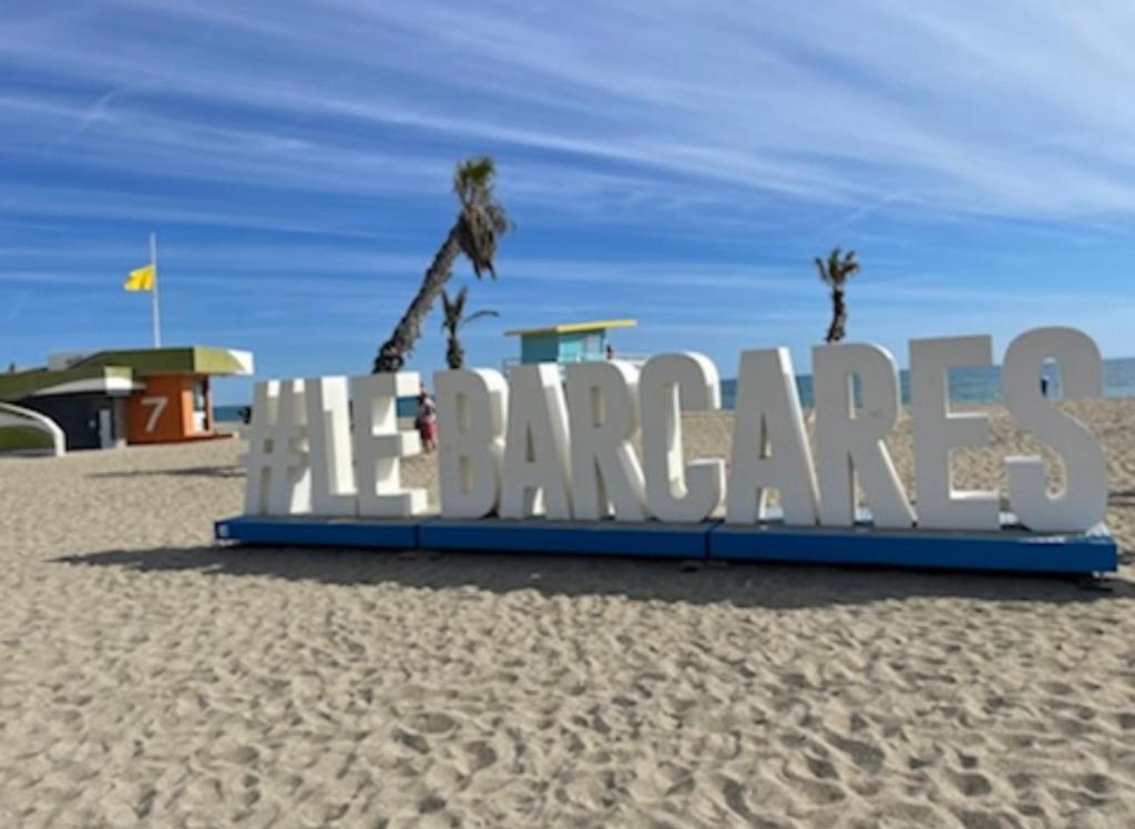 a sign on a beach with palm trees on it at Studio FRONT DE MER rénové in Le Barcarès