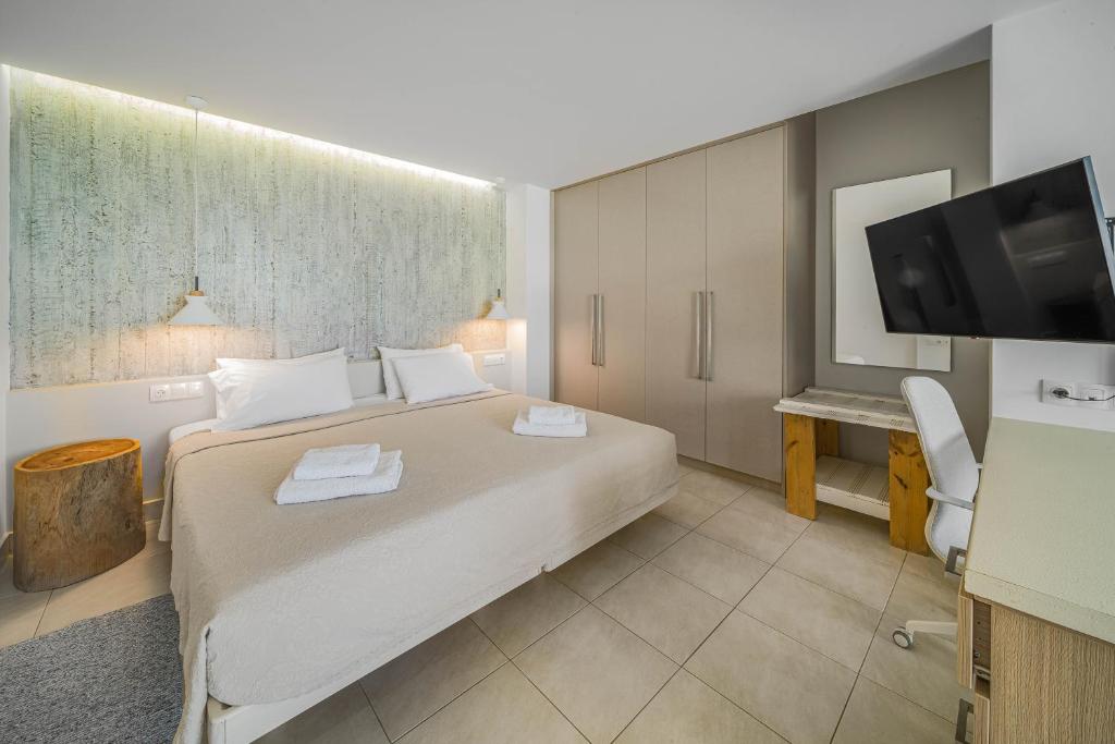 a hotel room with a bed and a flat screen tv at Junior suite by the beach Stalida in Stalida