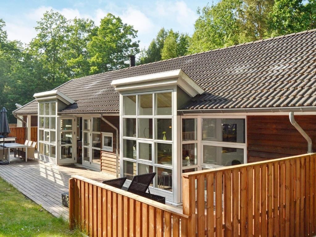 Cette maison dispose de grandes fenêtres et d'une terrasse en bois. dans l'établissement 10 person holiday home in Hasle, à Hasle