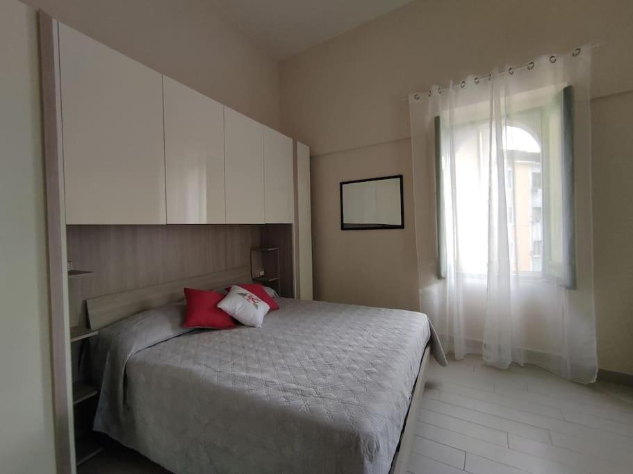 Un dormitorio con una cama con almohadas rojas y una ventana en La Torre, en Maiori
