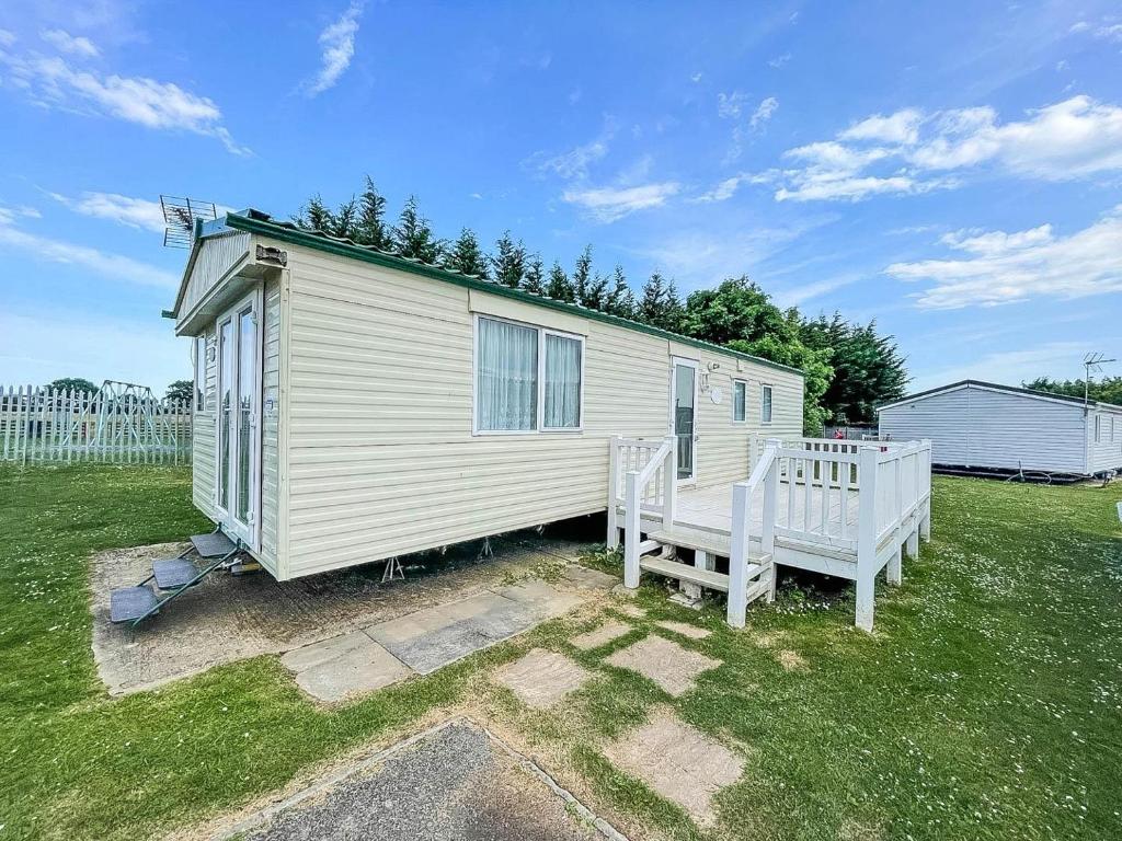 a tiny house with a bench in a yard at Caravan At Highfield Grange With Decking, Sleeps 6 Ref 26446ba in Clacton-on-Sea