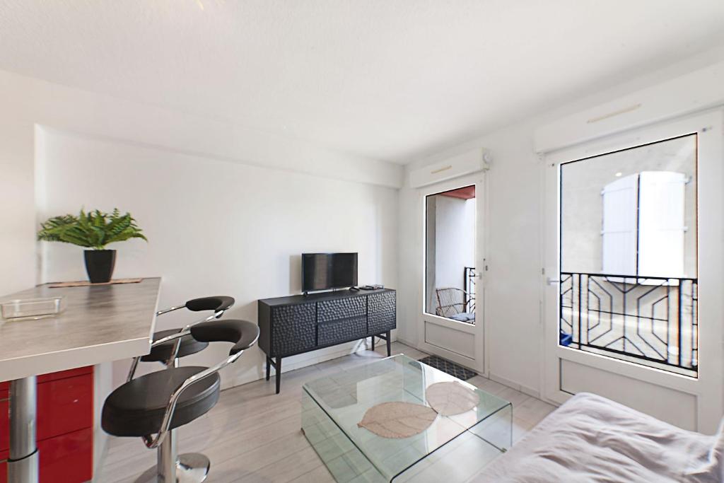 una sala de estar blanca con mesa de cristal y sillas en Aka Appart'Hotel " Le Petit Coin de Lavaur", en Lavaur