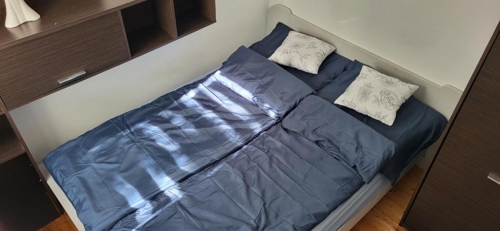 Una cama pequeña con sábanas azules y almohadas. en Szpitalna 9c en Suwałki