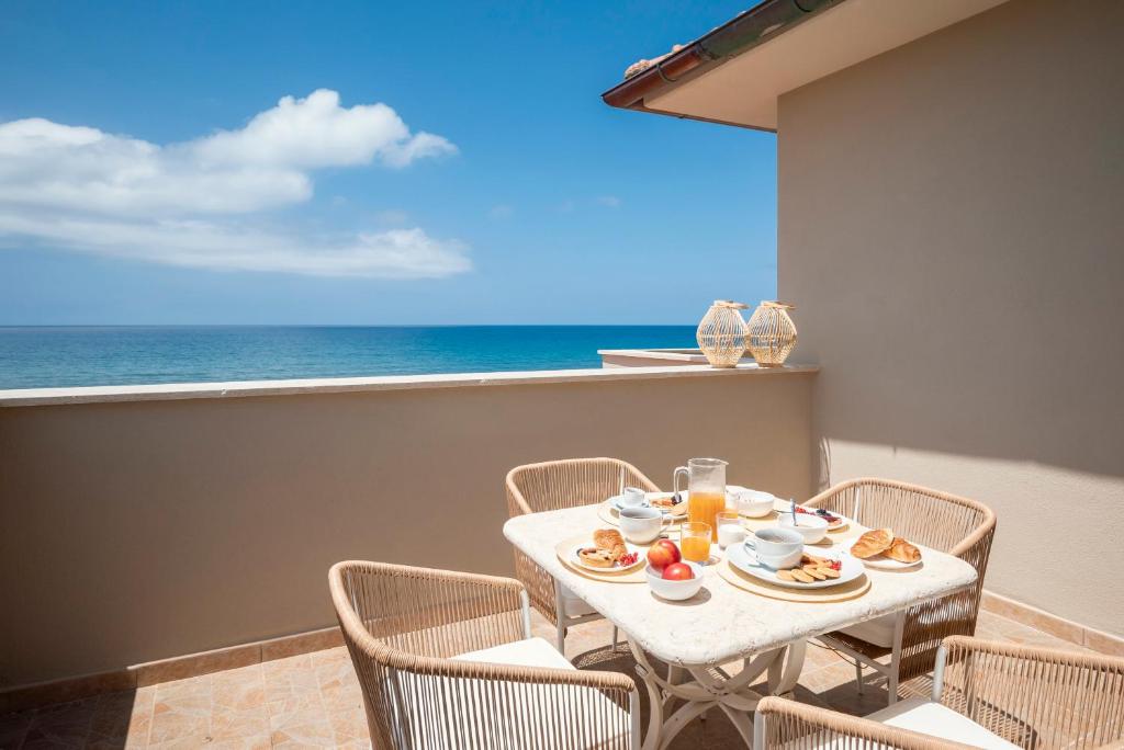 een tafel met eten en drinken op een balkon met uitzicht op de oceaan bij Zefiro Apartments in San Vincenzo