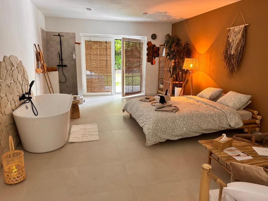 um quarto com uma cama grande e uma banheira em Coco Suite em Amay