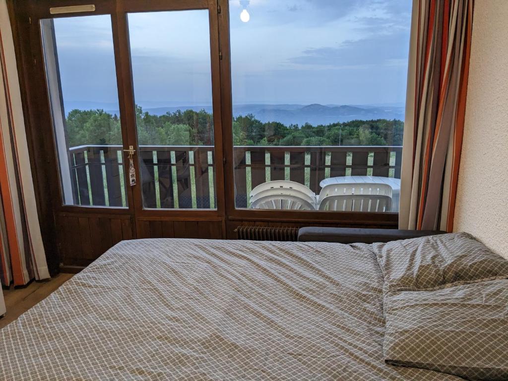 een slaapkamer met een bed en een groot raam bij Studio au coeur de la montagne in Thollon